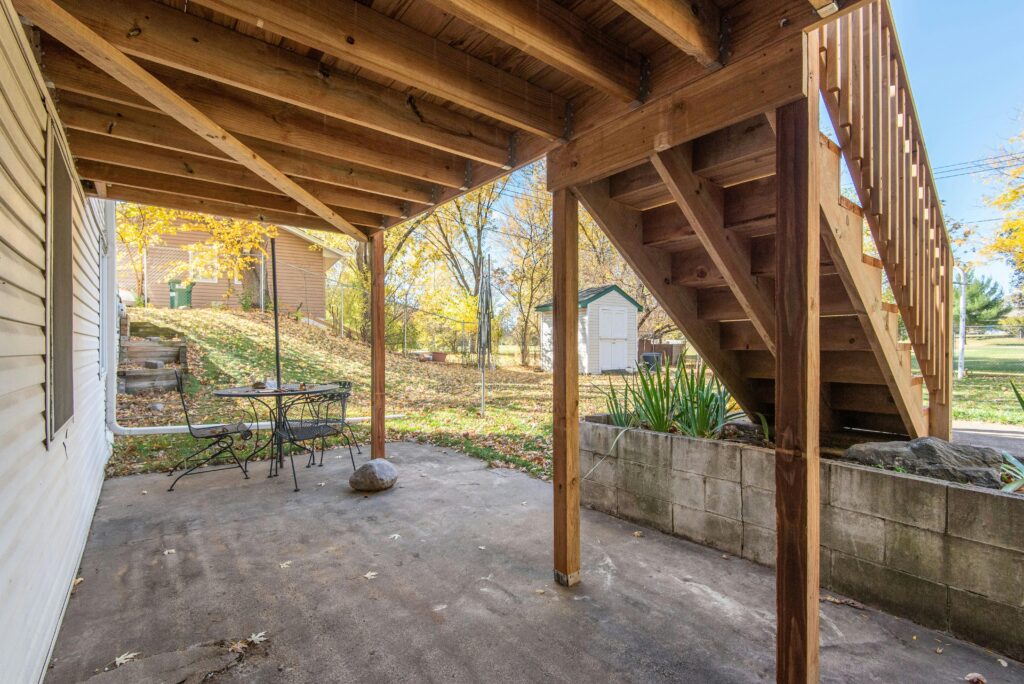 Outdoor wooden staircase leading to a backyard patio area in a residential setting.